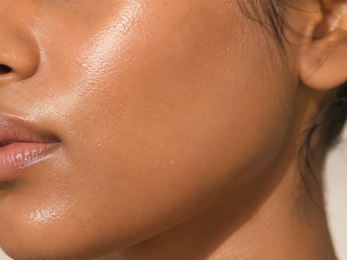 A close crop of a Sri Lankan woman's cheek and jaw, skin dewy and luminous in soft daylight.